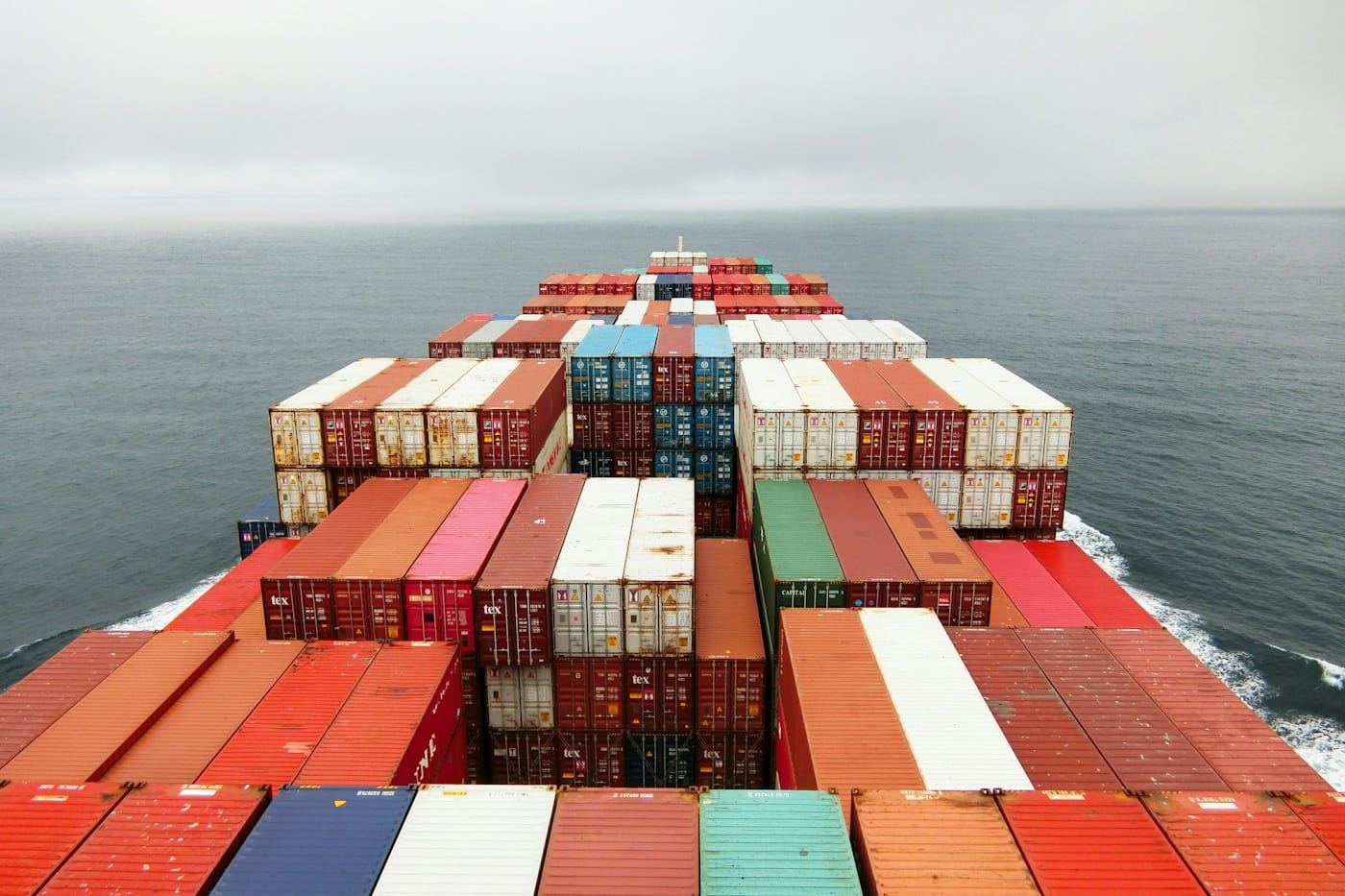The bow of a container ship stacked high with colourful shipping containers.